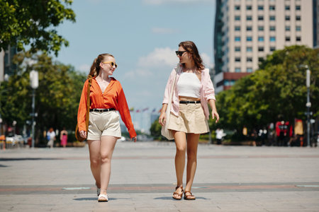 Two Women Walking Down City Street in Daylightの写真素材