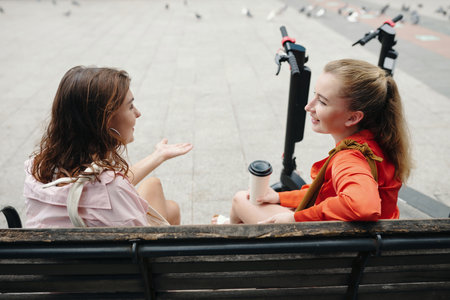 Having Conversation on Park Bench with Scooters Nearbyの写真素材