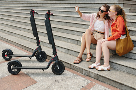Two Women Sitting on Steps Photographing Themselvesの写真素材
