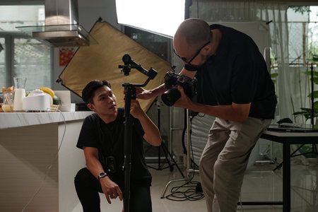 Assistant Helping Cameraman To Set Equipment
