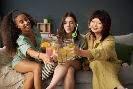 Three Young Women Clinking Glasses With Drinksの写真素材