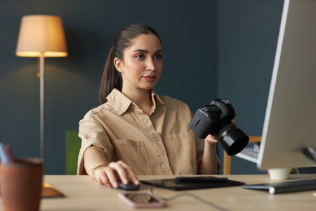 Editing Photos While Holding Camera in Modern Officeの写真素材