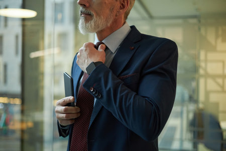 Mature Man in Suit Fixing His Tieの写真素材