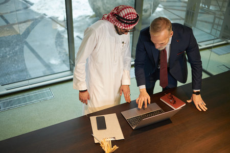 Two Diverse Businessmen Using Laptop In Office