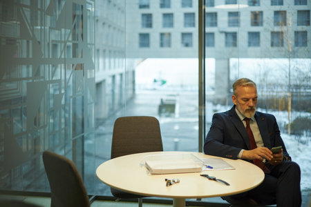 Middle-aged Businessman Scrolling Webpage On Smartphoneの写真素材