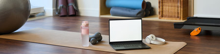 Clean, organized home gym setup including a yoga mat, water bottle, dumbbells, and a laptop surrounded by exercise props for a workout sessionの写真素材
