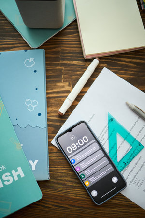 Modern student desk with smartphone with notifications, writing tools, document, pen and notebooks...