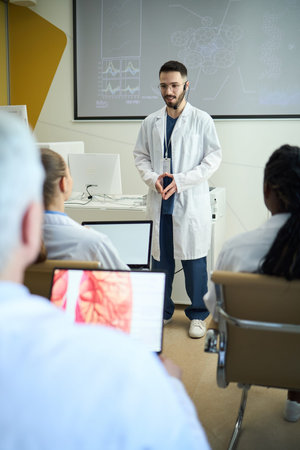 Educating a group of diverse students in modern laboratory room with presentation screens and...