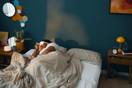 Person lying in bed after waking up in cozy bedroom setting with modern decor and warm lighting...