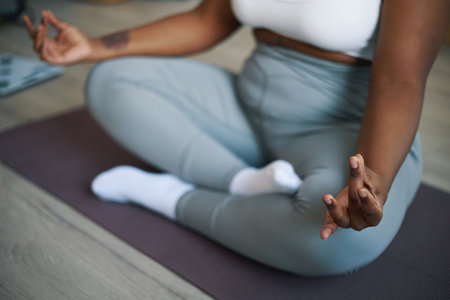 Individual practicing yoga meditation indoors, maintaining a calm and relaxed posture, with focus on hand in mudra gestureの写真素材