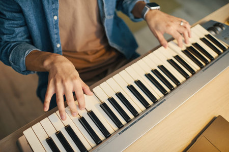 Close-up view of male hands skillfully playing melodies on electric keyboard. Detailed composition...