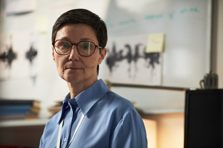 Portrait of middle aged Caucasian woman with short hair and glasses standing in front of whiteboard...