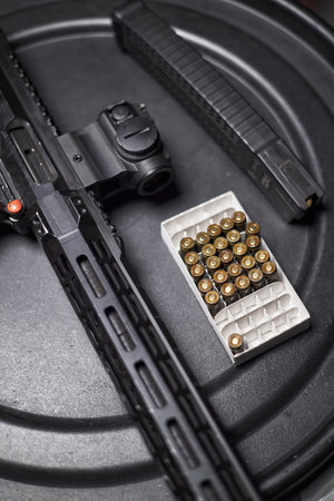 Closeup showing modern rifle with optical sight, two magazines, box of ammunition arranged on black...