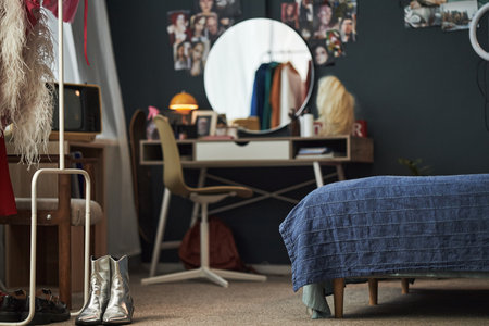 Creative Gen Z girl bedroom showing workspace with vanity mirror, clothing rack, and personal items suggesting teenage girl living in modern home environment, no people visibleの写真素材