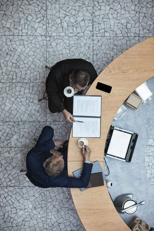 Overhead view of two businessmen discussing business strategy during office meeting in cafeteria....