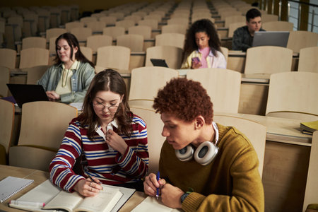 Group of multiethnic university students studying in lecture hall, young Caucasian woman and Black...
