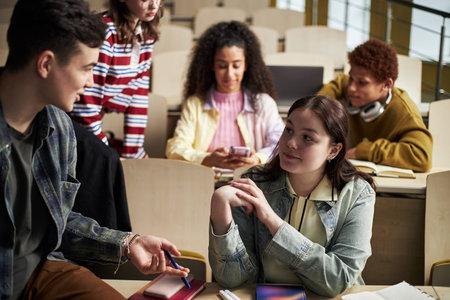 Group of multiethnic university students interacting in classroom, young Caucasian woman listening...