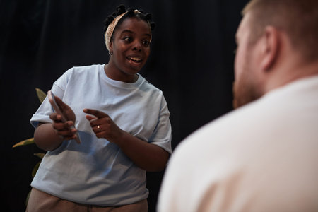 Young adult Black woman gesturing and speaking with young adult Caucasian man during intense conversation, both standing close together, expressing conflict in relationshipの写真素材