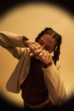 Portrait of young adult Black woman with braided hair showing fists adorned with multiple rings,...