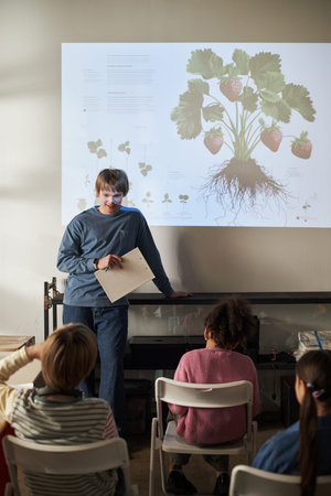 Caucasian middle aged man teaching group of diverse children about plant biology and strawberry...