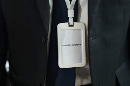 Anonymous man wearing suit and tie attending business conference with identification badge hanging from neck, close up showing upper torso and conference passの写真素材