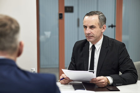 Middle aged Caucasian male executive holding documents conducting business meeting or job interview...