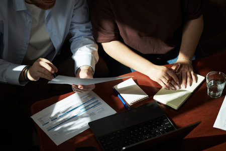 Caucasian young adult man and Caucasian young adult woman reviewing financial documents together at...