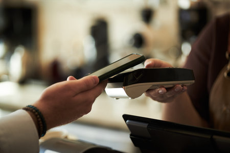Caucasian young adult man holding smartphone making contactless payment using digital wallet at...
