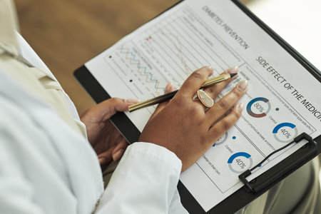 Closeup of Black female medical professional holding clipboard, analyzing diabetes prevention chart...