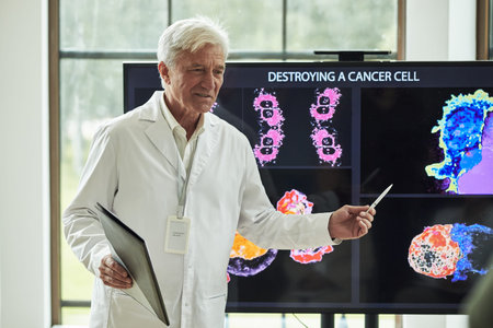 Senior Caucasian male professor presenting scientific research, holding digital tablet and pen,...