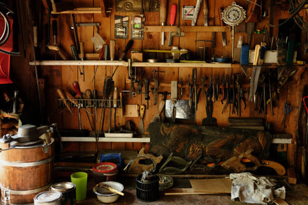 Wooden workshop wall displaying variety of hand tools including hammers, saws, screwdrivers, pliers,...