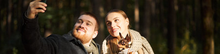 Header of Caucasian young adult man and Caucasian young adult woman taking selfie together outdoors...