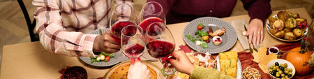 Header of diverse group of young and middle aged friends clinking wine glasses over Thanksgiving...