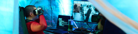 Header of young adult Caucasian woman sitting at desk wearing virtual reality headset, interacting...