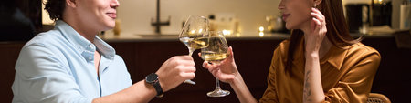 Header of young Caucasian man and young Caucasian woman sitting together clinking wine glasses,...