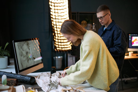 Caucasian young woman arranging dried flowers on table while Caucasian young man standing nearby in...