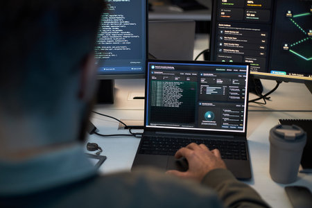 Caucasian man monitoring cybersecurity dashboard and code across laptop and multiple screens, analyzing network threats and system data. For IT security, data protection, SOC marketing