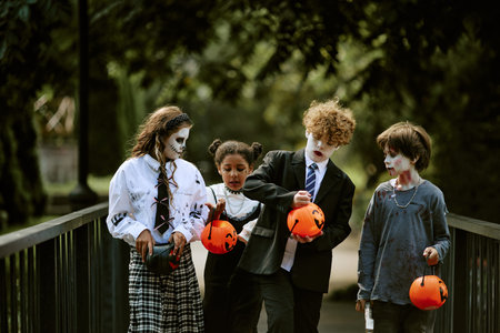 Diverse group of kids in Halloween costumes walking outdoors with pumpkin buckets, collecting candies. Image suitable for seasonal holiday advertising and autumn event promotion