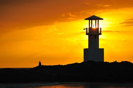 Lighthouse searchlight beam through marine at sunset の写真素材