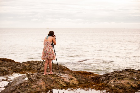 woman photographer takes photo of the beautiful seascapeの写真素材