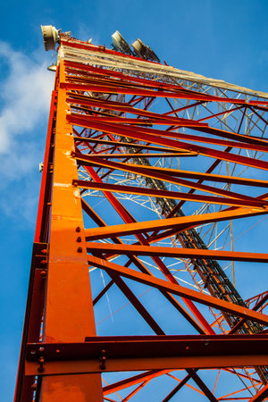 Red white telecommunication tower against blue sky - bottom viewの写真素材