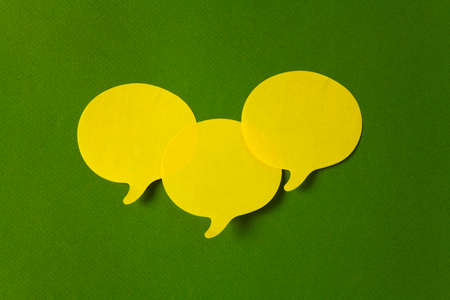 Yellow stickers with shape of speech bubble on green backgroundの写真素材