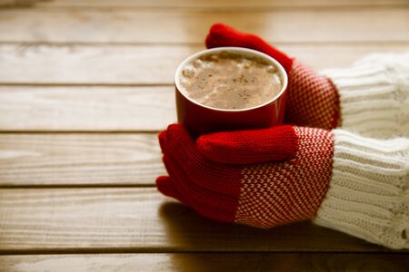 Hands in gloves holding hot cup of coffeeの写真素材