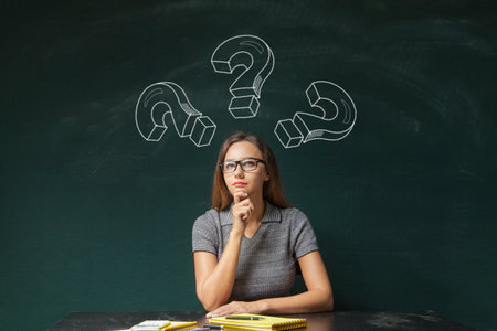 Businesswoman and question mark drawn in chalk on blackboard