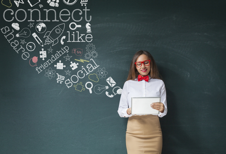Social Media concept - business woman using tablet with social media text and icon on the blackboardの写真素材