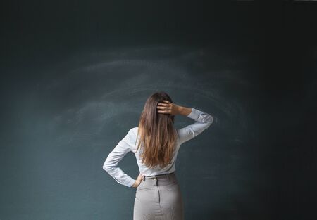 Businesswoman looking at an empty green chalkboardの写真素材