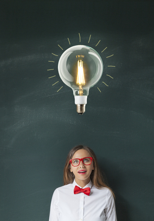Thinking woman in front of light bulb drawing blackboardの写真素材