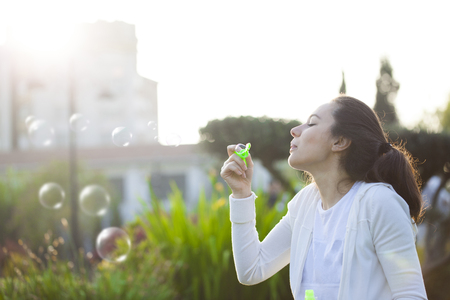 Young woman having fun and blowing bubbles outdoors.の写真素材