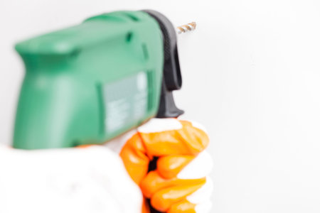 Handyman holding electric power driller, drilling hole in a white concrete wall