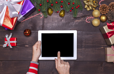 Woman hands using digital tablet on wooden plank with christmas ornamentの写真素材